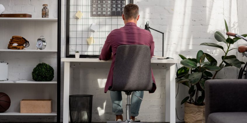 back view of man sitting on chair and working at home office