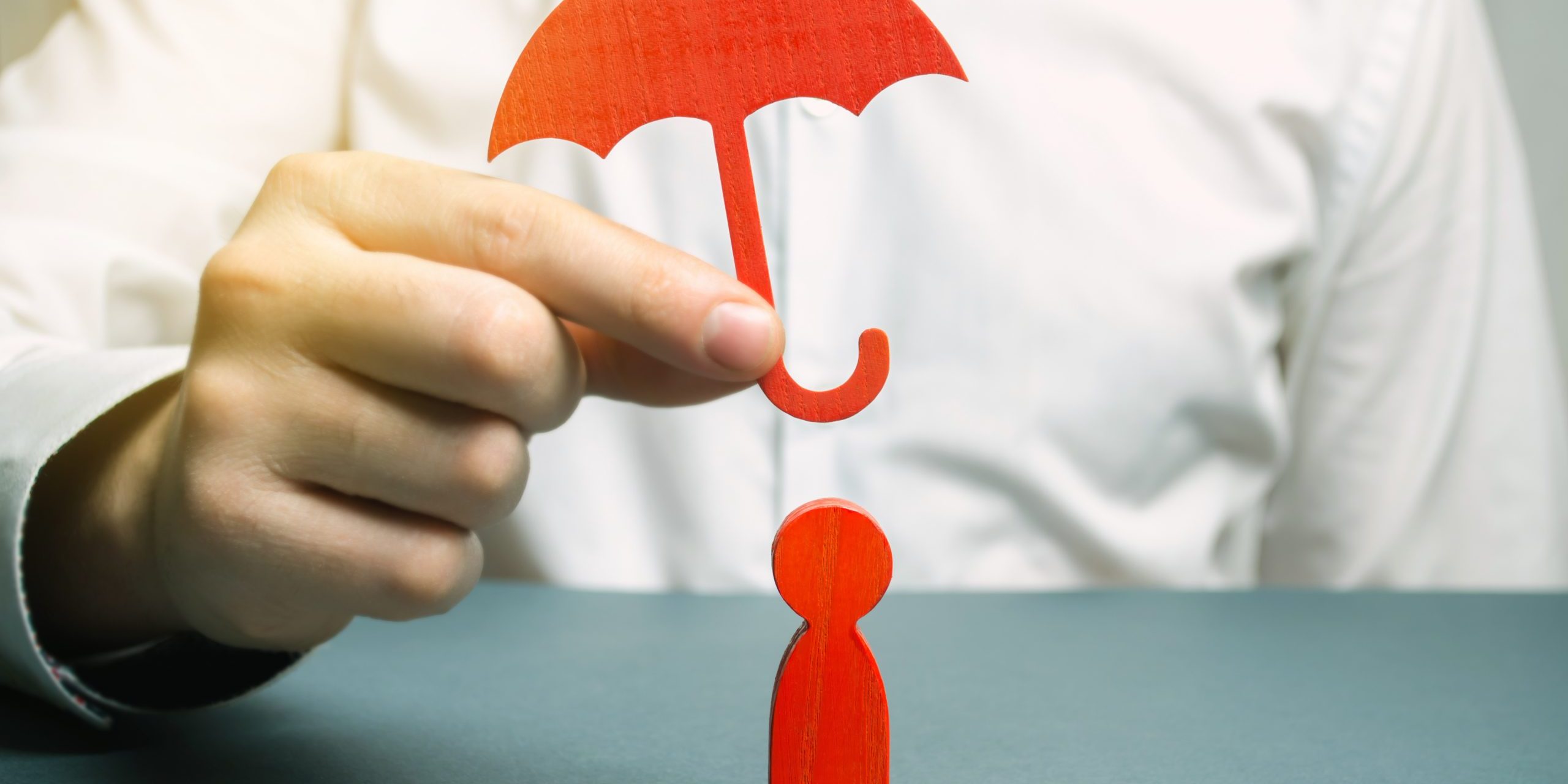 An insurance agent holds a red umbrella over a human figure. Concept of life and health insurance. Unconditional income. Protection of rights. Security. Legal assistance. Golden parachute