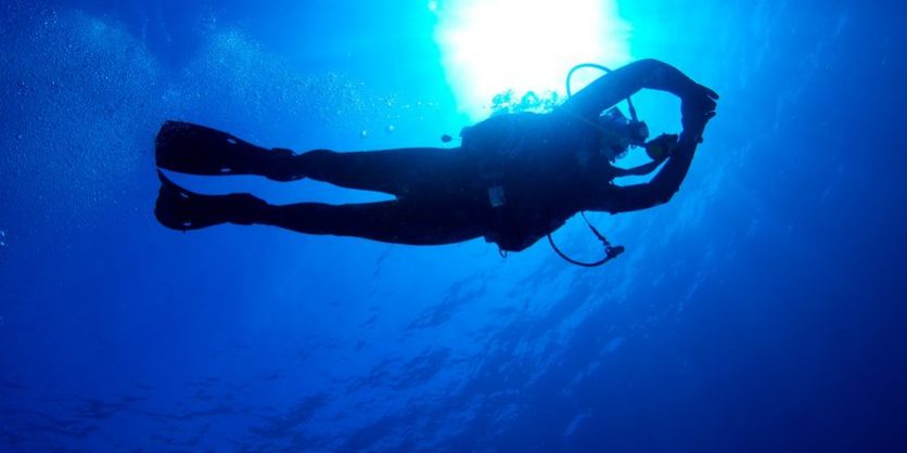 15126775 – silhouette of diver with sun disk behind