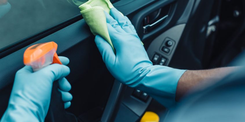 cropped view of car cleaner holding rag and spray bottle while cleaning car door