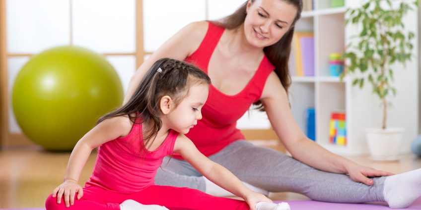 Mother and daughter doing fitness exercises on mat at home