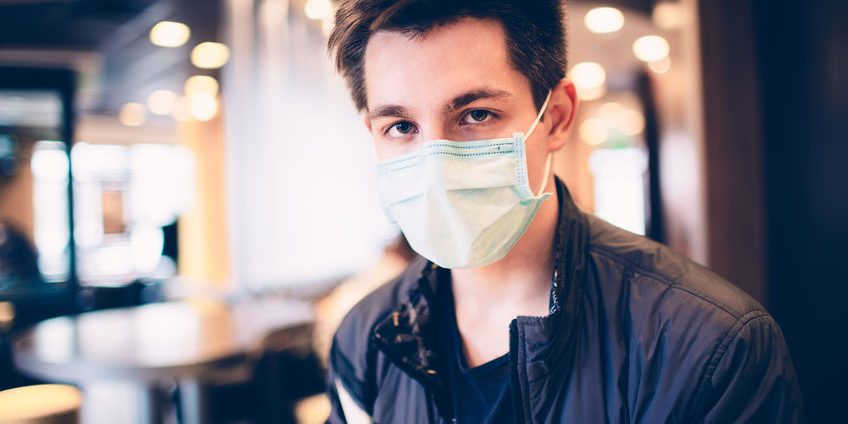 Man wearing medical face mask in the a restaurant. Male wearing face mask, protection from virus infection.