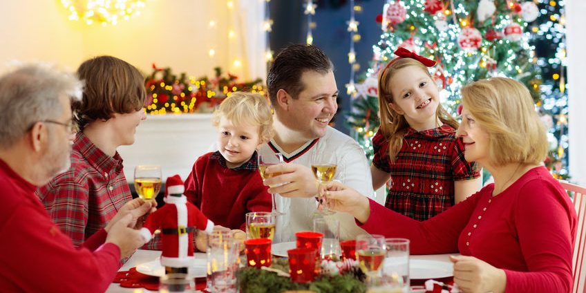 Family with kids having Christmas dinner at tree