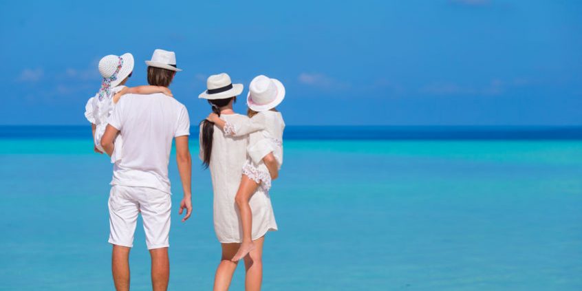 Young family of four on white beach