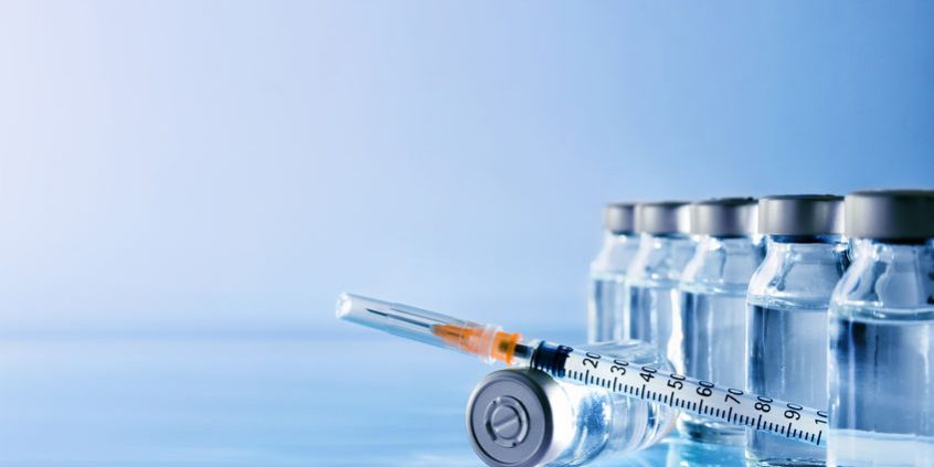 Vials group and syringe on table with blue background