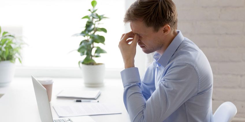 Tired businessman massaging nose bridge, feeling eyes strain