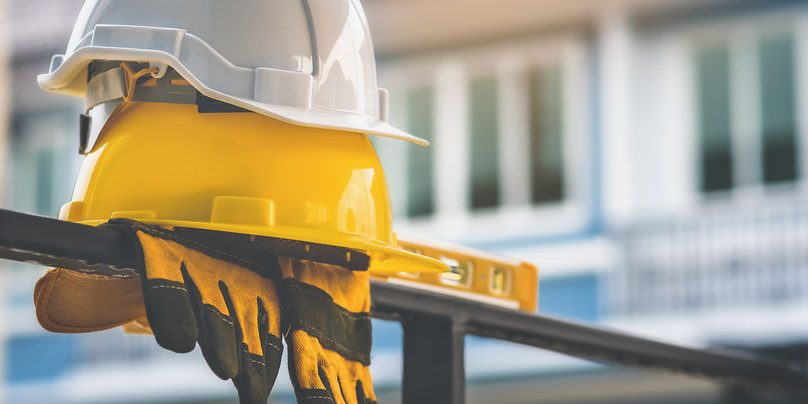 White and yellow helmet  with gloves are placed on steel house f