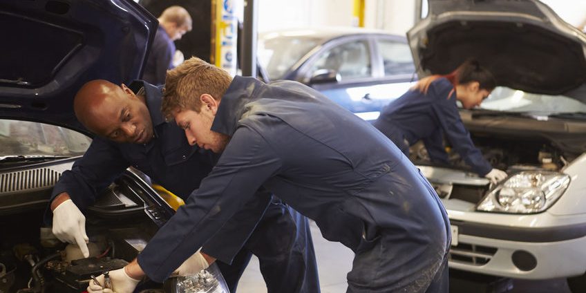 Teacher Helping Student Training To Be Car Mechanics