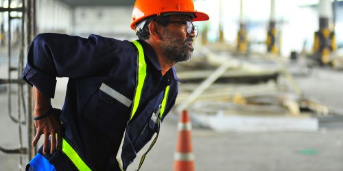 Senior,Worker,With,Backache,At,Construction,Site,In,Warehouse.