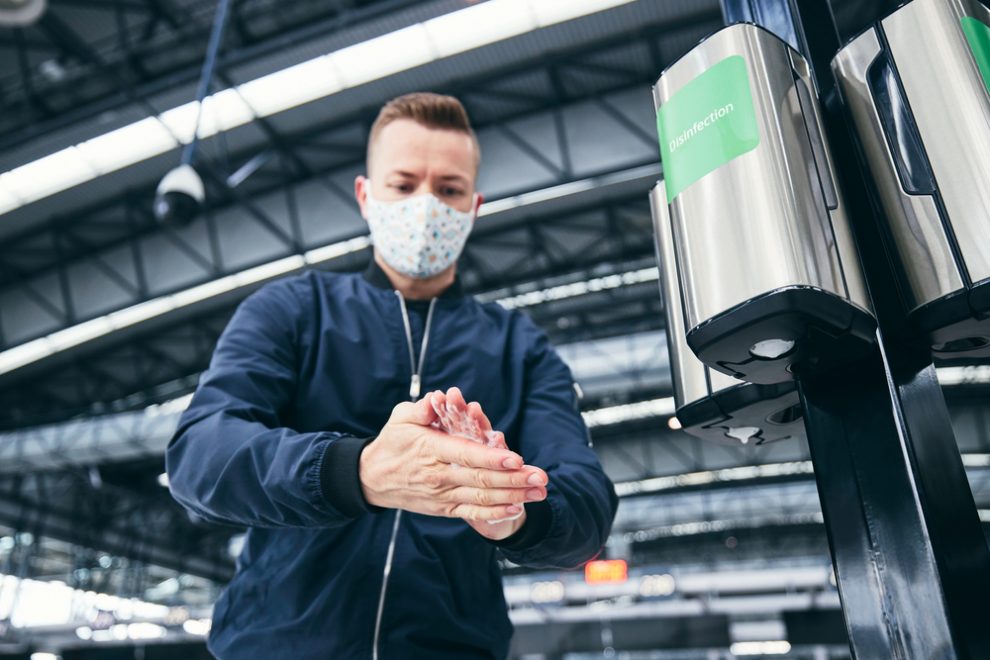 Man,Wearing,Face,Mask,And,Using,Hand,Sanitizer,At,Airport.