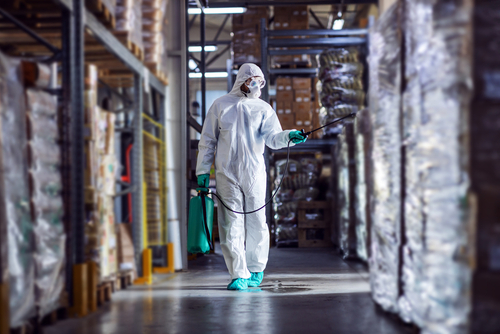 Man,In,Protective,Suit,And,Mask,Disinfecting,Warehouse,Full,Of